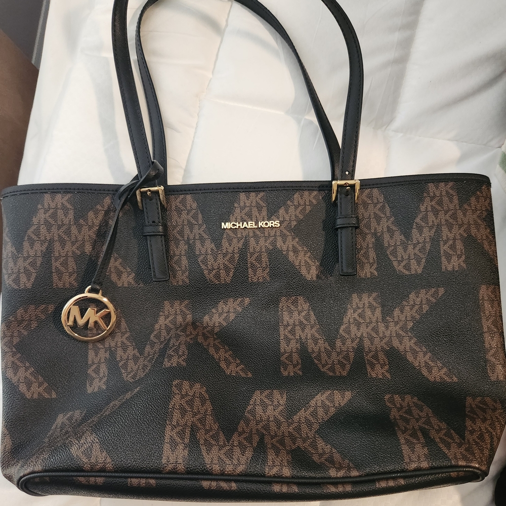 Michael Kors Black and Brown Tote Bag with Monogram Pattern, Straps Are Worn.